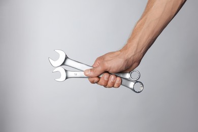 Auto mechanic with wrenches on grey background, closeup