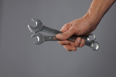 Photo of Auto mechanic with wrenches on grey background, closeup