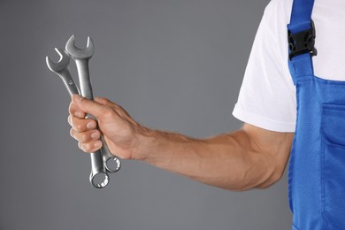 Auto mechanic with wrenches on grey background, closeup