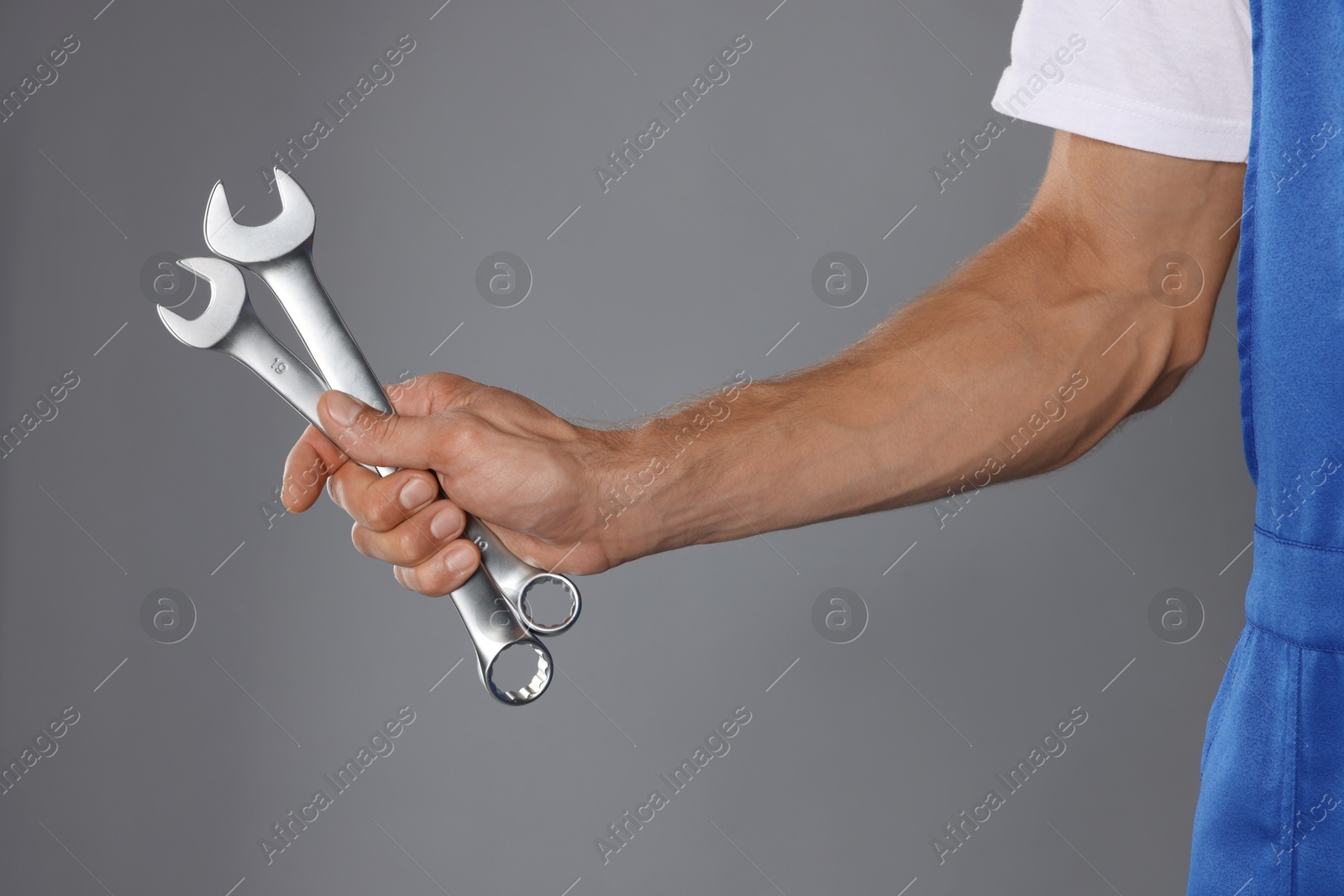 Photo of Auto mechanic with wrenches on grey background, closeup