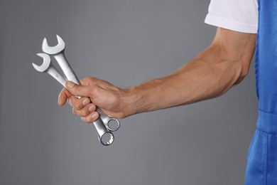 Photo of Auto mechanic with wrenches on grey background, closeup