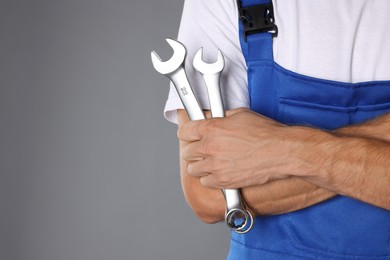 Auto mechanic with wrenches on grey background, closeup. Space for text