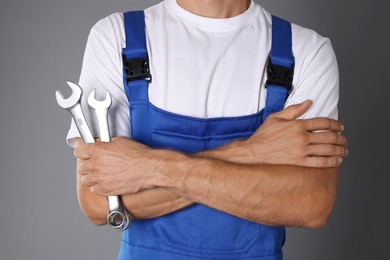 Photo of Auto mechanic with wrenches on grey background, closeup