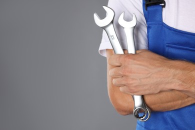 Auto mechanic with wrenches on grey background, closeup. Space for text