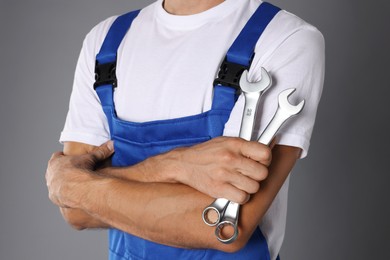 Auto mechanic with wrenches on grey background, closeup