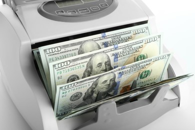 Photo of Money counter machine with dollar banknotes on white background, closeup