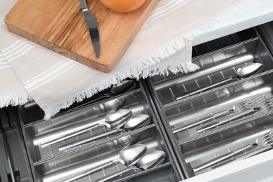 Photo of Box with cutlery in drawer, above view. Kitchen utensils storage