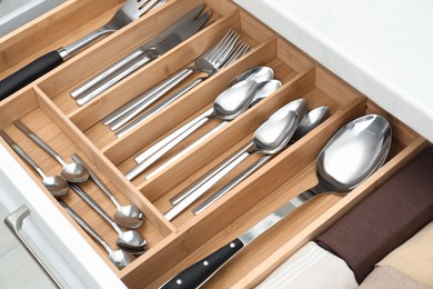 Photo of Box with cutlery in drawer, closeup. Kitchen utensils storage