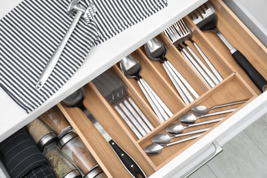 Photo of Box with cutlery in drawer, closeup. Kitchen utensils storage