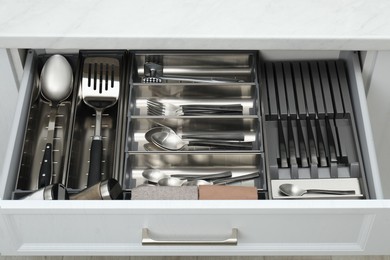 Photo of Box with cutlery in drawer, closeup. Kitchen utensils storage