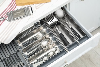 Photo of Box with cutlery in drawer, closeup. Kitchen utensils storage