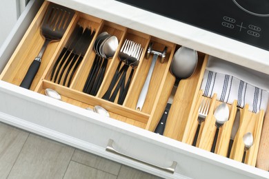 Photo of Box with cutlery in drawer, closeup. Kitchen utensils storage