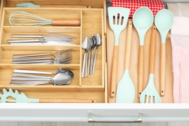 Photo of Box with cutlery in drawer, closeup. Kitchen utensils storage