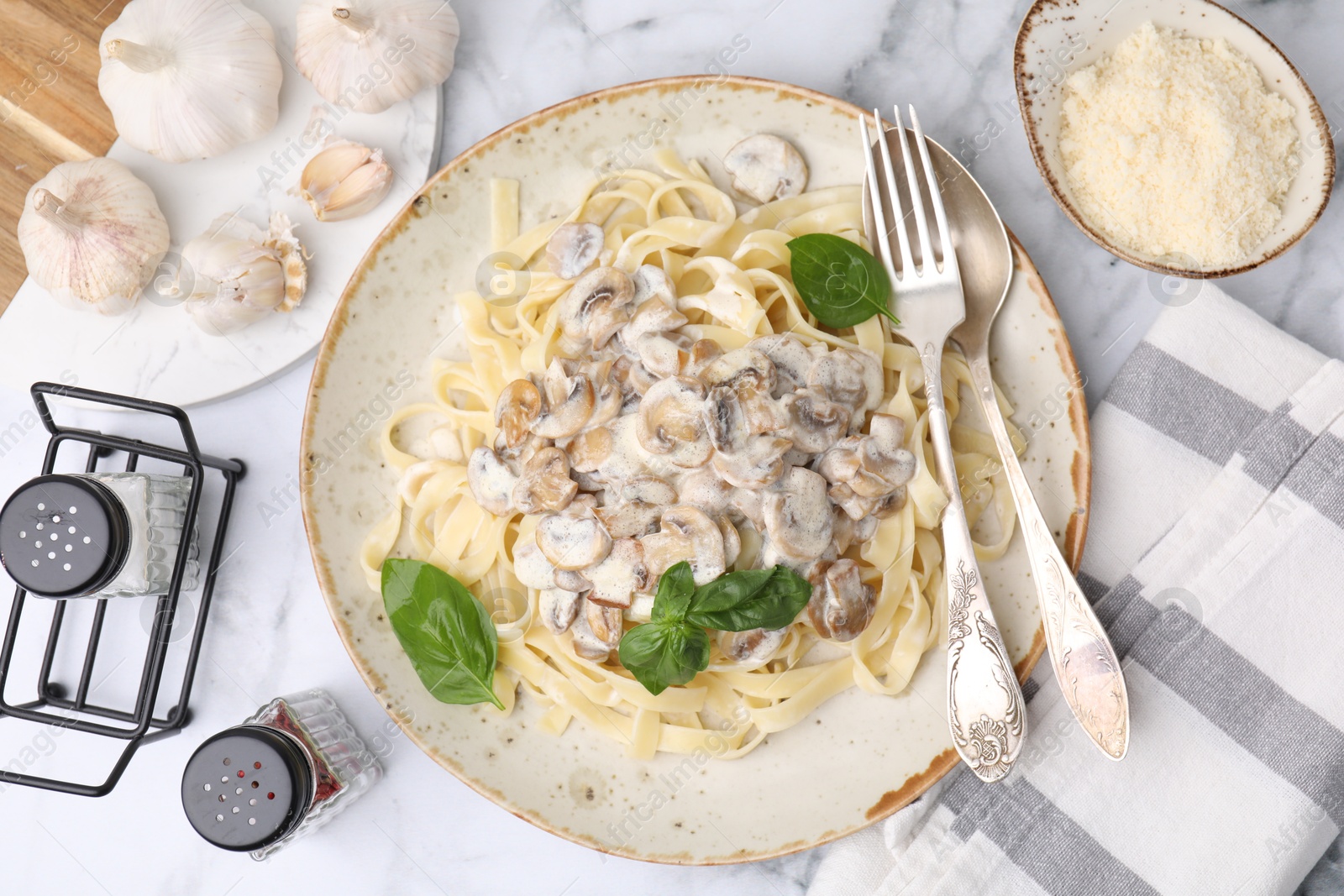 Photo of Delicious pasta with mushrooms served on white marble table, flat lay