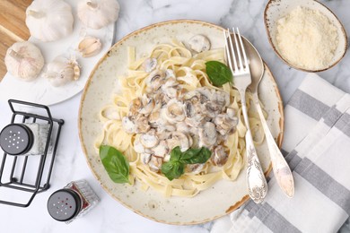 Photo of Delicious pasta with mushrooms served on white marble table, flat lay