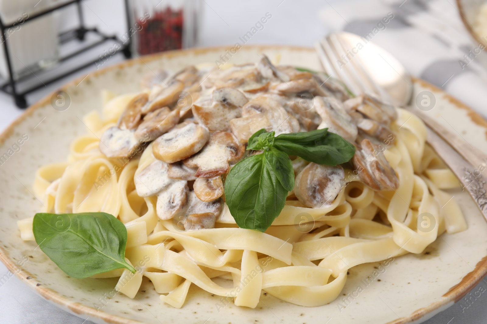 Photo of Delicious pasta with mushrooms and basil on table, closeup