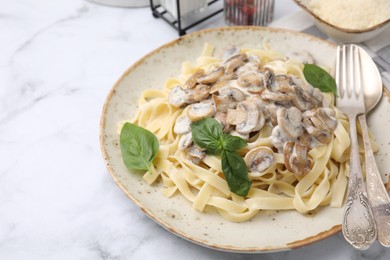 Photo of Delicious pasta with mushrooms and basil served on white marble table, closeup