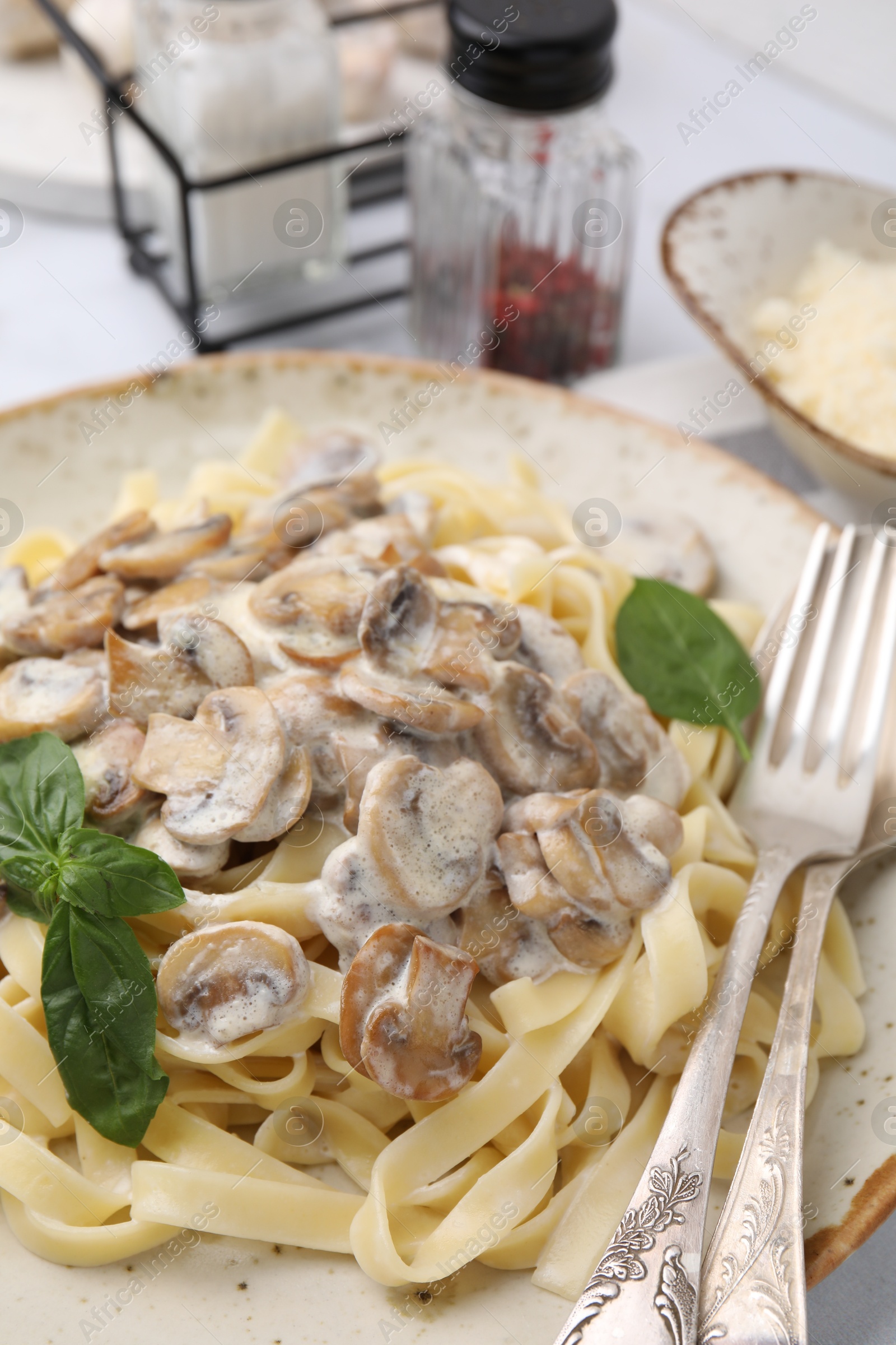 Photo of Delicious pasta with mushrooms and basil served on table, closeup