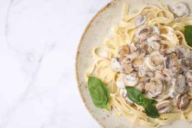 Photo of Delicious pasta with mushrooms and basil on white marble table, top view. Space for text