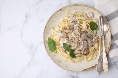 Photo of Delicious pasta with mushrooms and basil served on white marble table, top view. Space for text