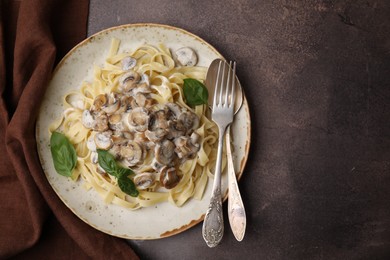 Photo of Delicious pasta with mushrooms and basil served on brown table, top view. Space for text