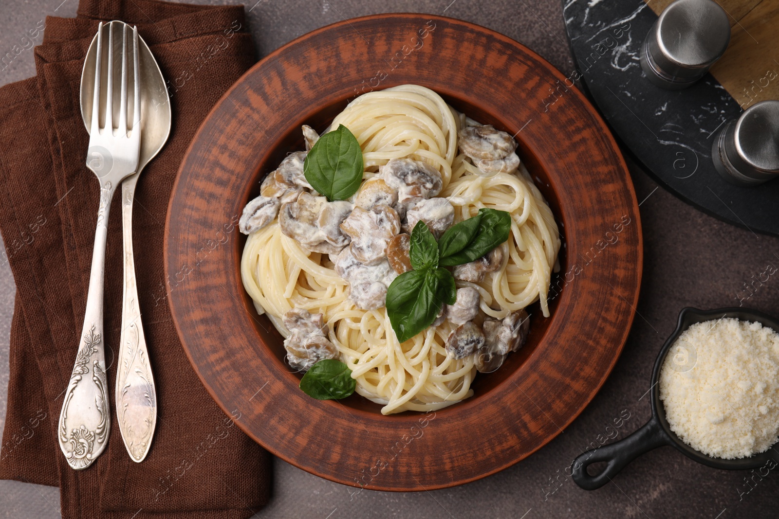 Photo of Delicious pasta with mushrooms and basil served on brown table, flat lay