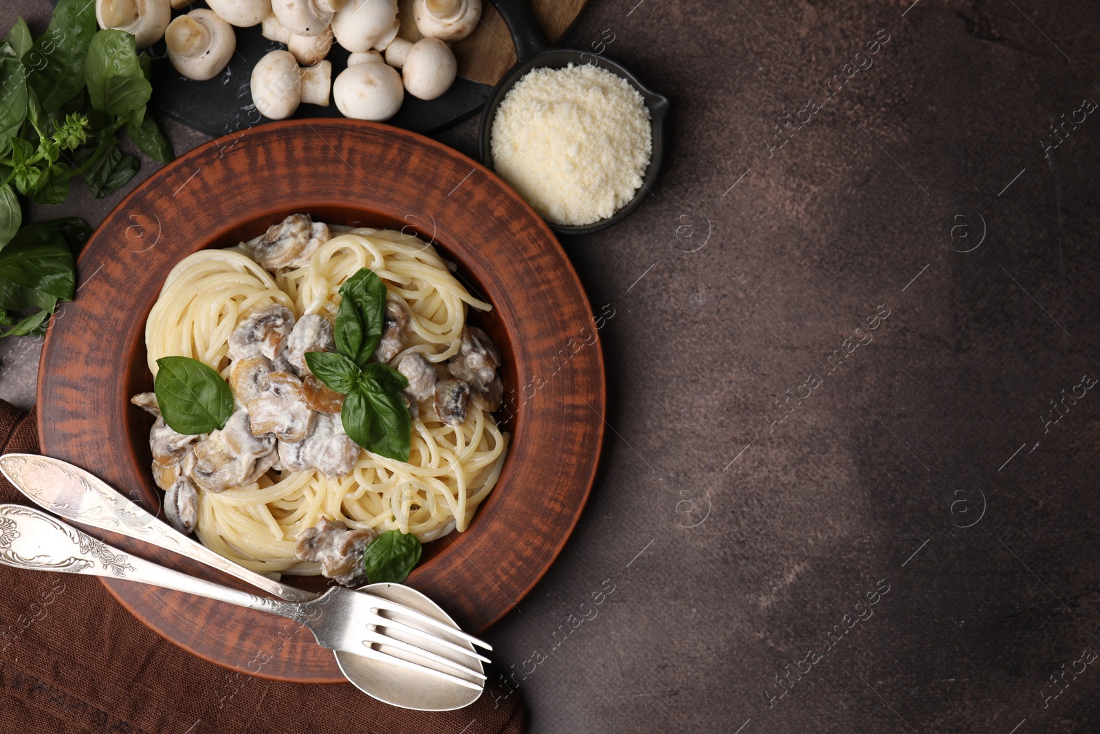 Photo of Delicious pasta with mushrooms and basil served on brown table, flat lay. Space for text