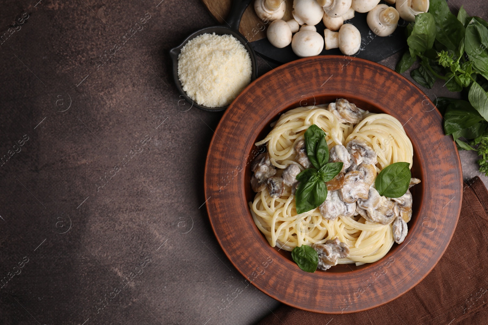 Photo of Delicious pasta with mushrooms and ingredients on brown table, flat lay. Space for text