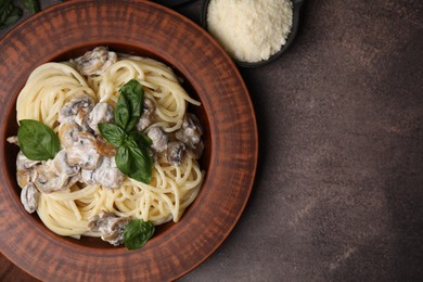 Photo of Delicious pasta with mushrooms and basil on brown table, flat lay. Space for text