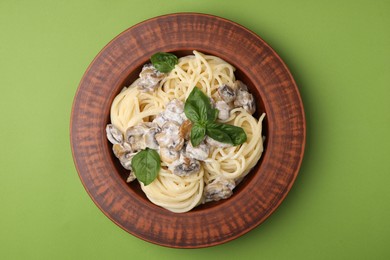 Delicious pasta with mushrooms and basil on light green background, top view