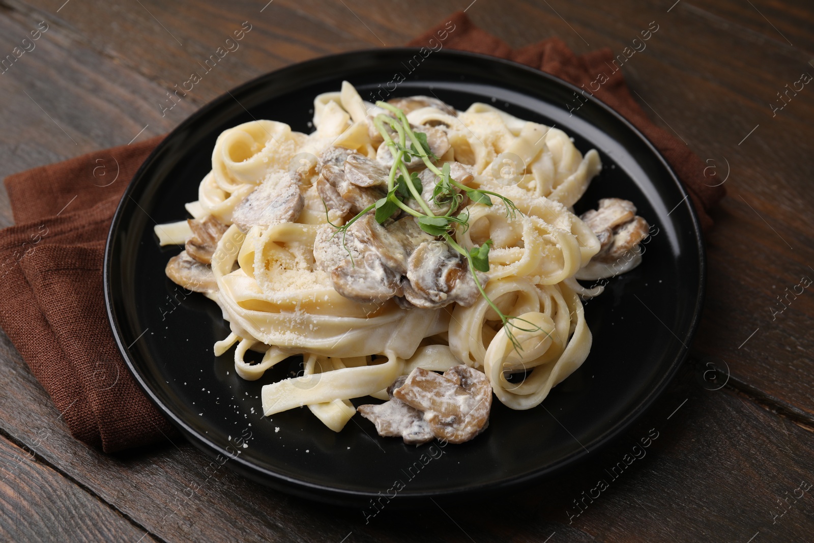 Photo of Delicious pasta with mushrooms on wooden table, closeup