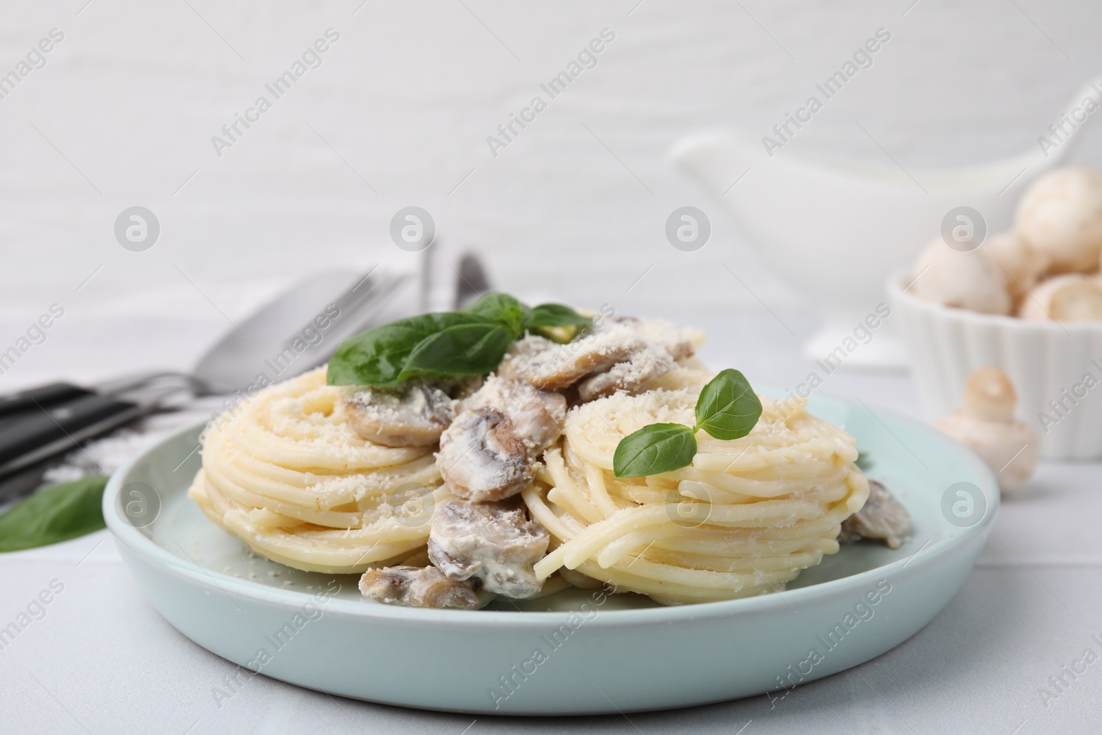 Photo of Delicious pasta with mushrooms and basil on white table, closeup