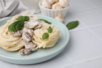 Photo of Delicious pasta with mushrooms and basil on white tiled table, closeup. Space for text