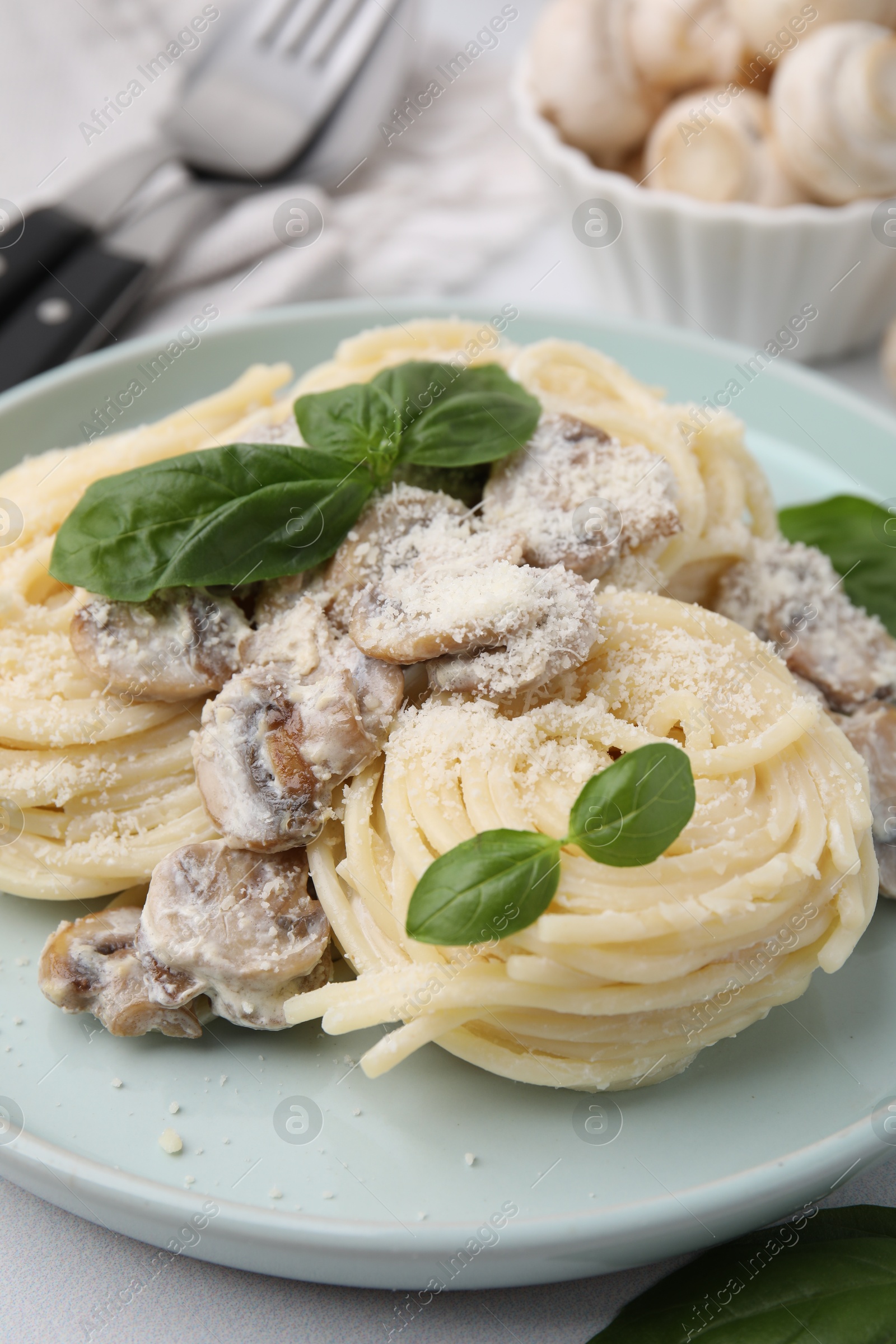 Photo of Delicious pasta with mushrooms and basil on table, closeup