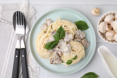 Photo of Delicious pasta with mushrooms and basil served on white tiled table, flat lay