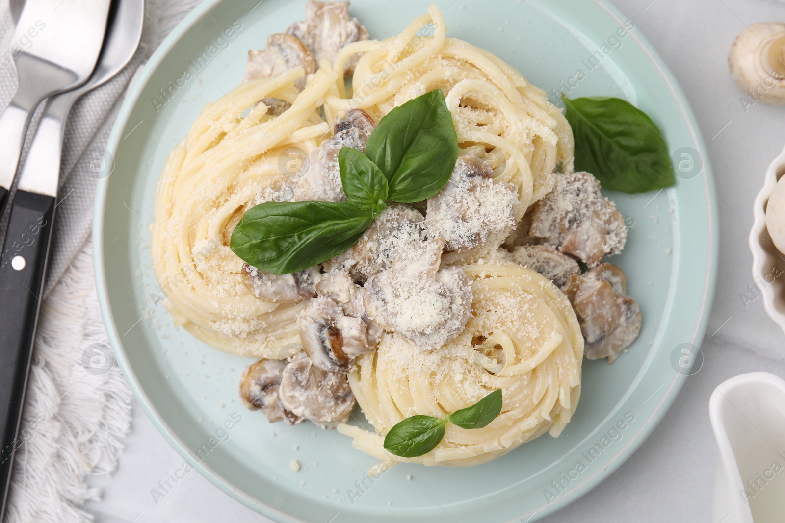 Photo of Delicious pasta with mushrooms and basil served on white tiled table, flat lay