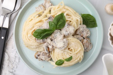 Photo of Delicious pasta with mushrooms and basil served on white tiled table, flat lay