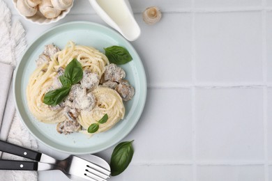 Photo of Delicious pasta with mushrooms and basil served on white tiled table, flat lay. Space for text