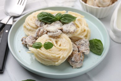 Photo of Delicious pasta with mushrooms and basil on white table, closeup