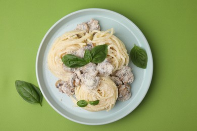 Photo of Delicious pasta with mushrooms and basil on light green background, top view