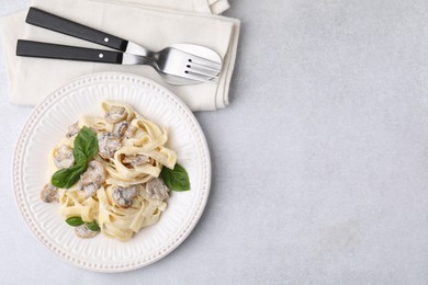 Photo of Delicious pasta with mushrooms and basil served on light table, flat lay. Space for text