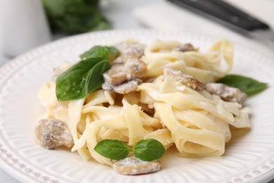 Photo of Delicious pasta with mushrooms and basil on table, closeup