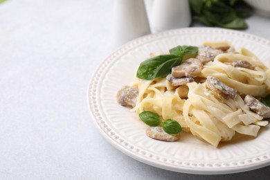 Photo of Delicious pasta with mushrooms and basil on light table, closeup. Space for text