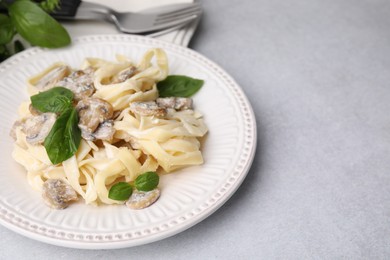 Photo of Delicious pasta with mushrooms and basil on light table, closeup. Space for text