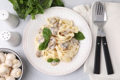 Photo of Delicious pasta with mushrooms and basil served on light table, flat lay