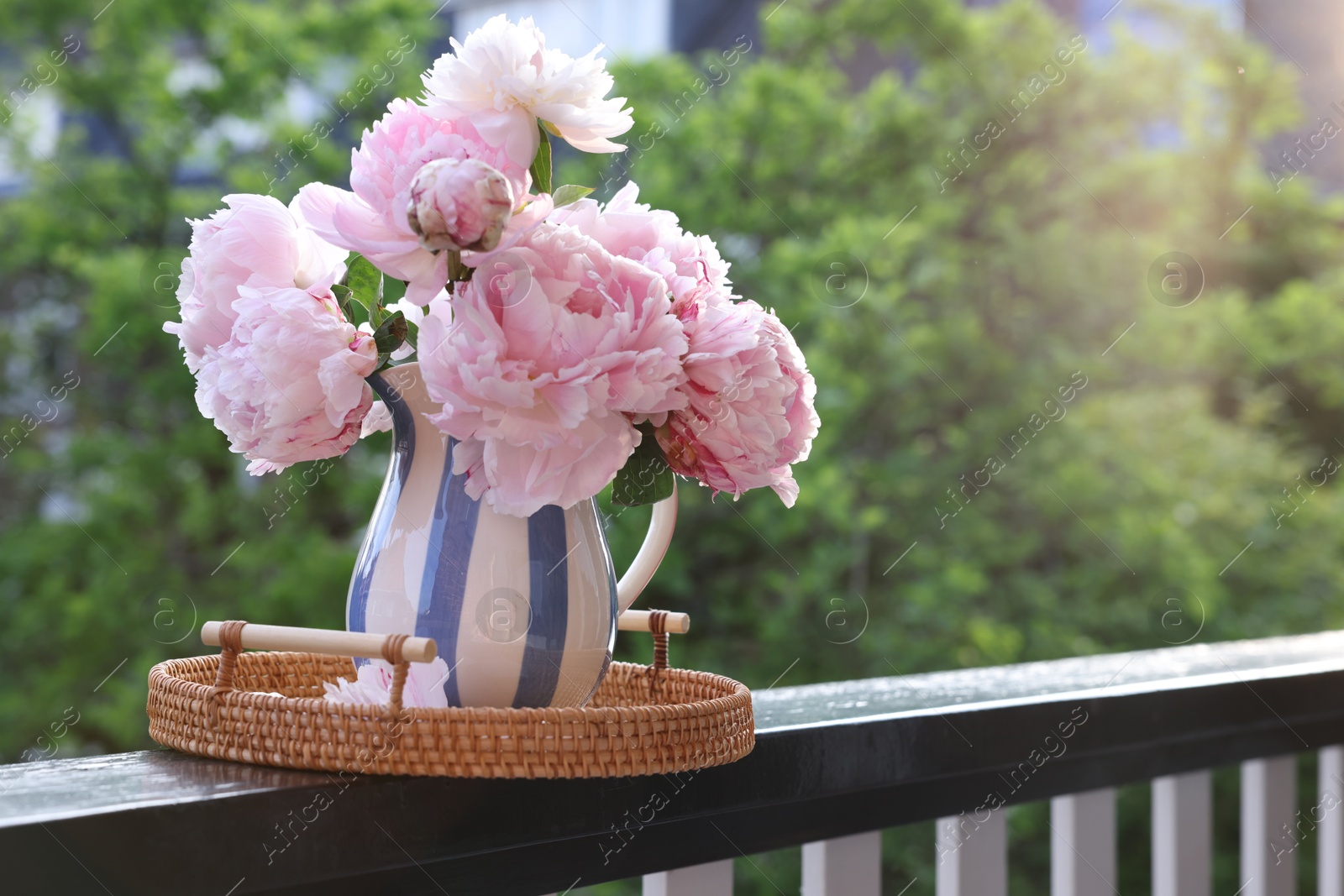 Photo of Beautiful pink peony flowers in vase on balcony railing outdoors