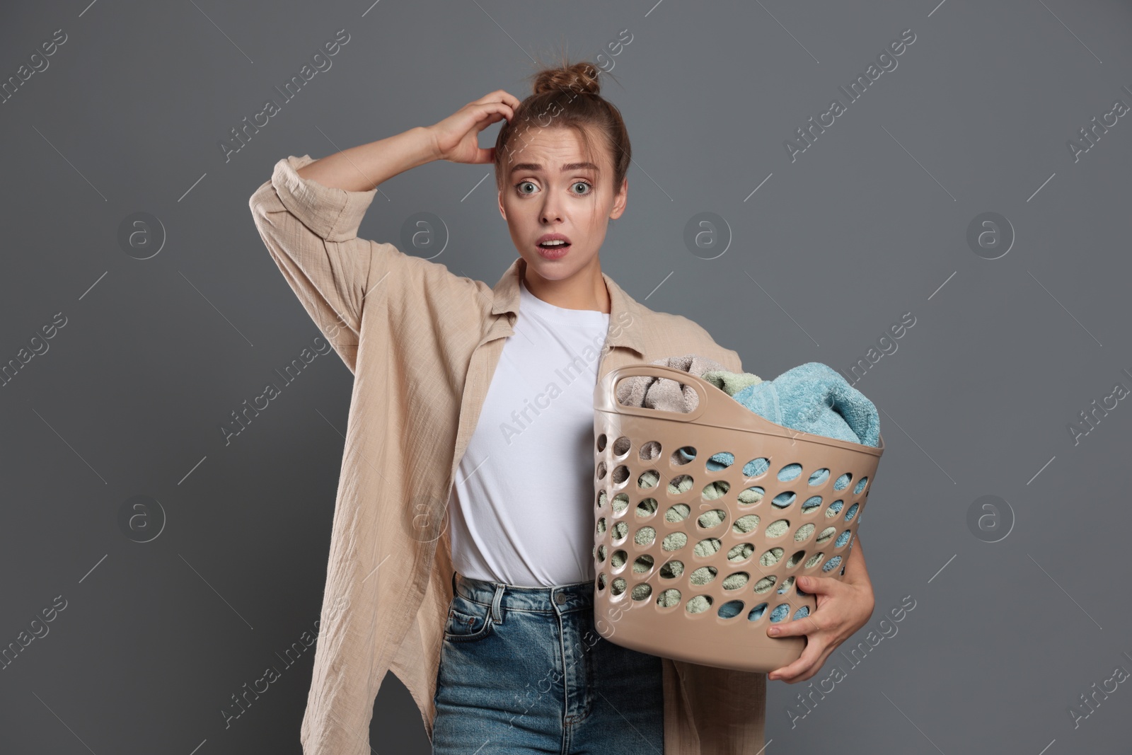 Photo of Tired housewife with basket full of laundry on grey background