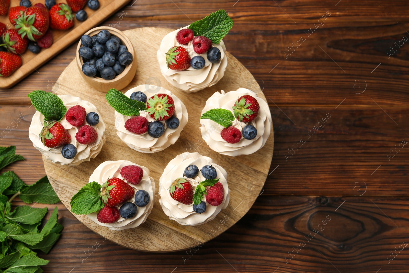 Photo of Tasty cupcakes with different berries and mint on wooden table, flat lay. Space for text