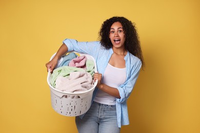 Shocked woman with basket full of laundry on yellow background