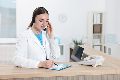 Photo of Professional receptionist working at wooden desk in hospital